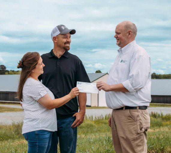 man giving check to couple